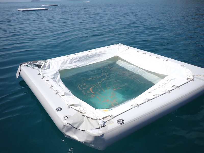 a floating pool collecting coral spawn visible as coloured slicks on the surface of the water