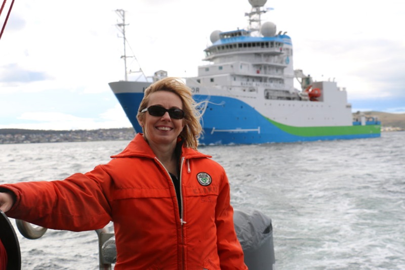 Tony Moate stands in front of the Investigator ship in the background, docked in the bay