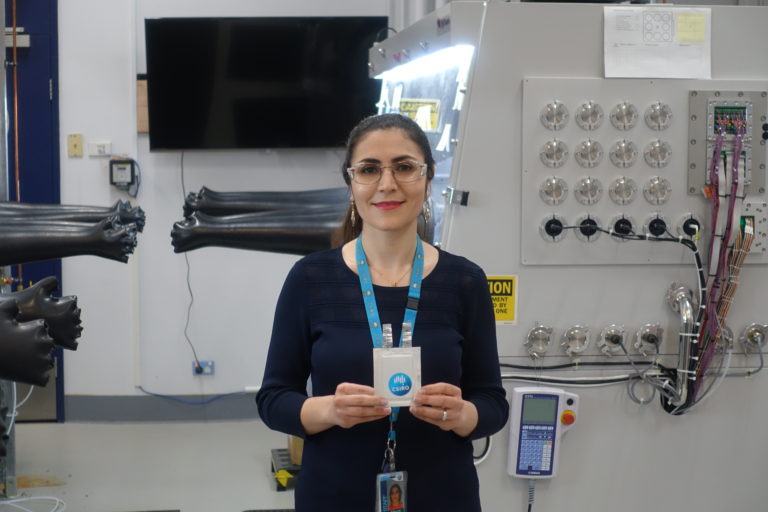 Dr Marzi Barghamadi standing in a lab holding a CSIRO lanyard. Breaking through the glass ceiling. 