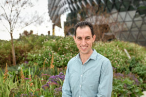 An image of a man standing in front of a large building