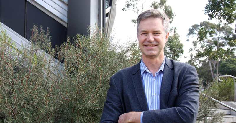 A male COVID-19 expert standing outside in a suit with his arms crossed