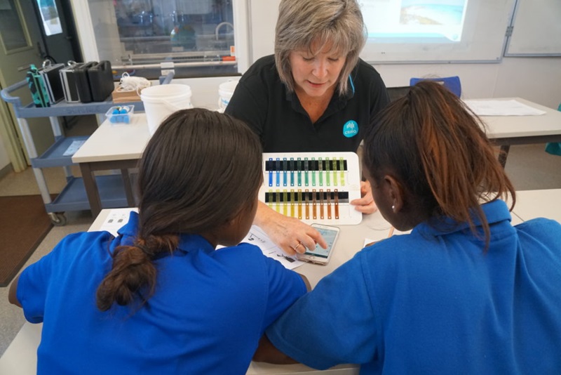 Woman showing the Eye On Water app to two students