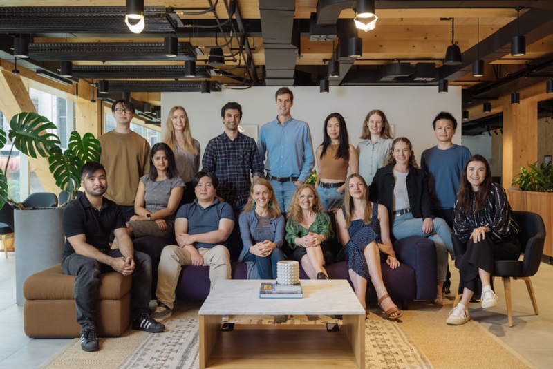 Pandemic pivot. HowToo team. Image of 15 people seated in a group in an office. 