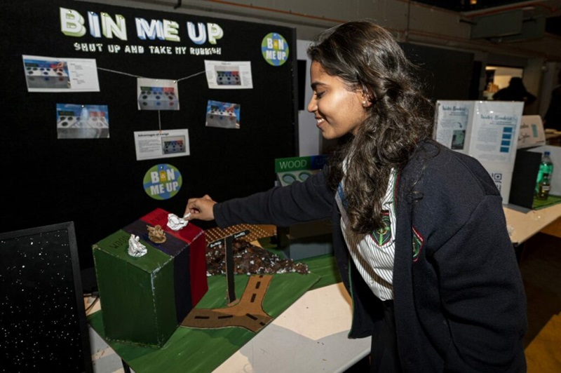 A student putting rubbish into a small bin as part of a demonstration titled "Bin Me Up".