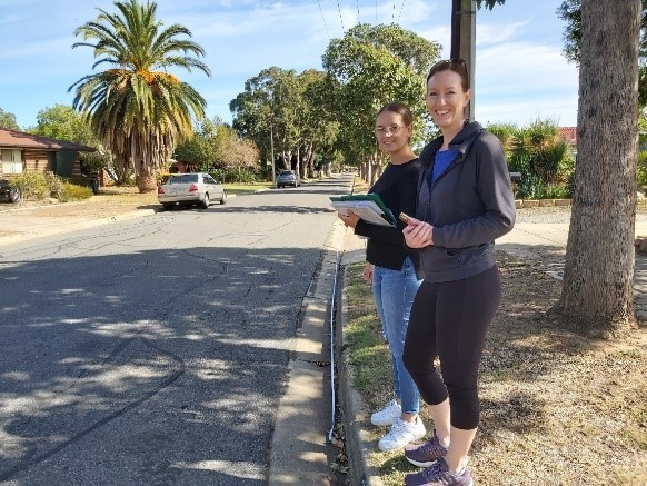 Researcher standing on the side of the road with clipboards as part of a rubbish data survey