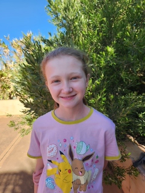 Young girl standing outside, smiling at the camera.</p><p>