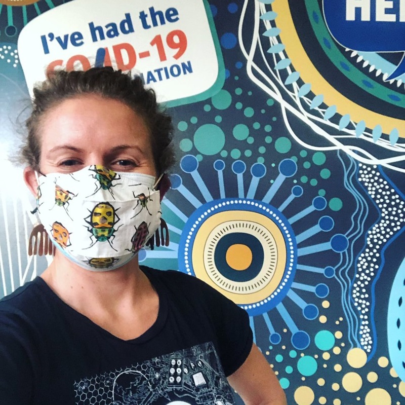 Woman with insect mask on smiling in CSIRO shirt. Showing of Music you can get vaccinated to