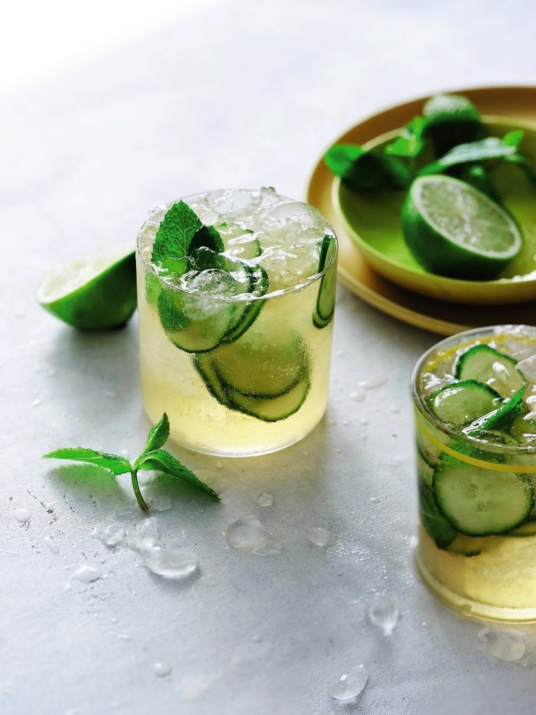 Two glasses of Mojito Kombucha Mocktail topped with cucumber and lime