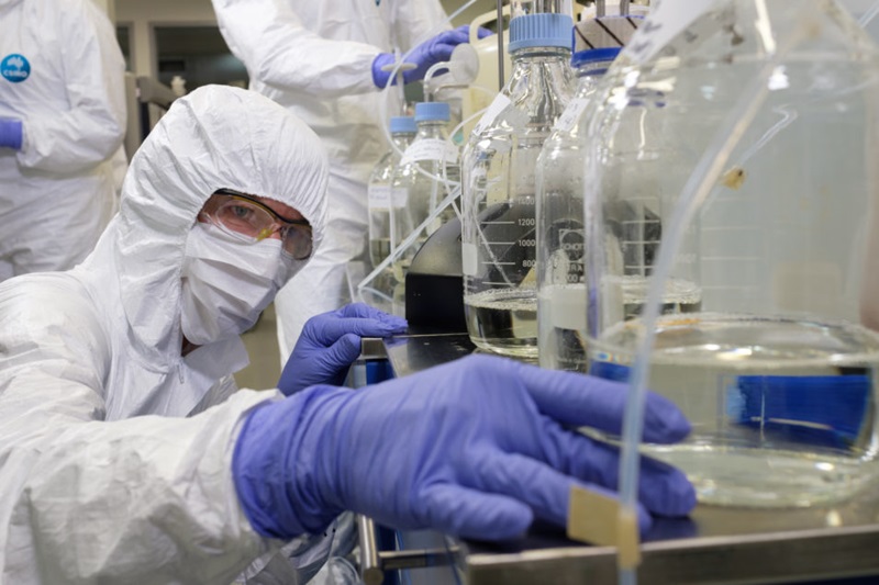 A researcher checks on their work in the lab while wearing full protective gear.
