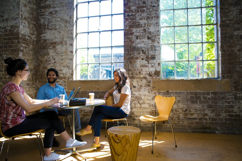 Three people sitting at a table, smiling in conversation. 