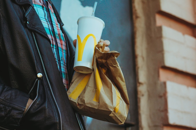 close up of person holding mcdonalds bag and drink cup