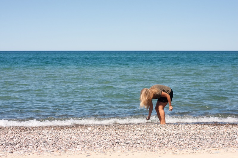 a person picking something up on the shoreline of a beach