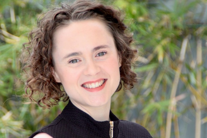A woman with curly brown hair smiling at the camera