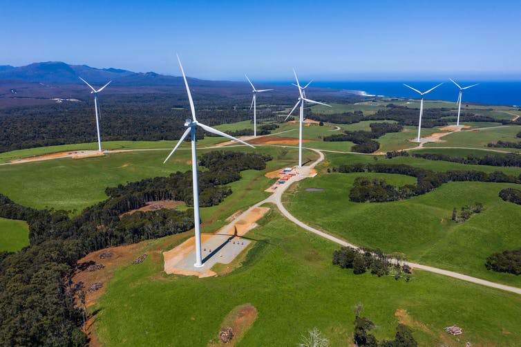 A wind farm with several wind turbines near the sea.
