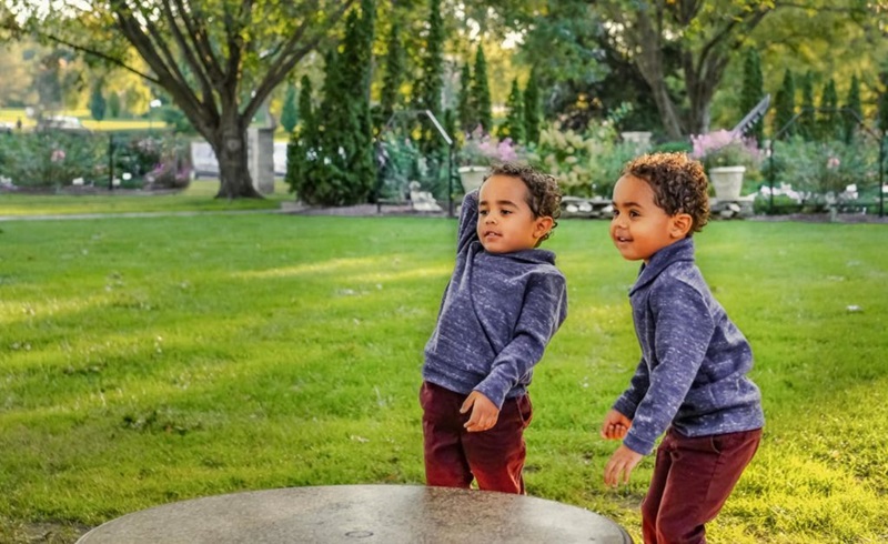 Two children playing in a green park outside.