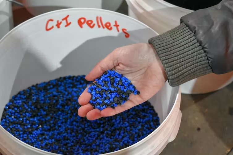 A photo showing a person holding tiny blue and black plastic pellets. 