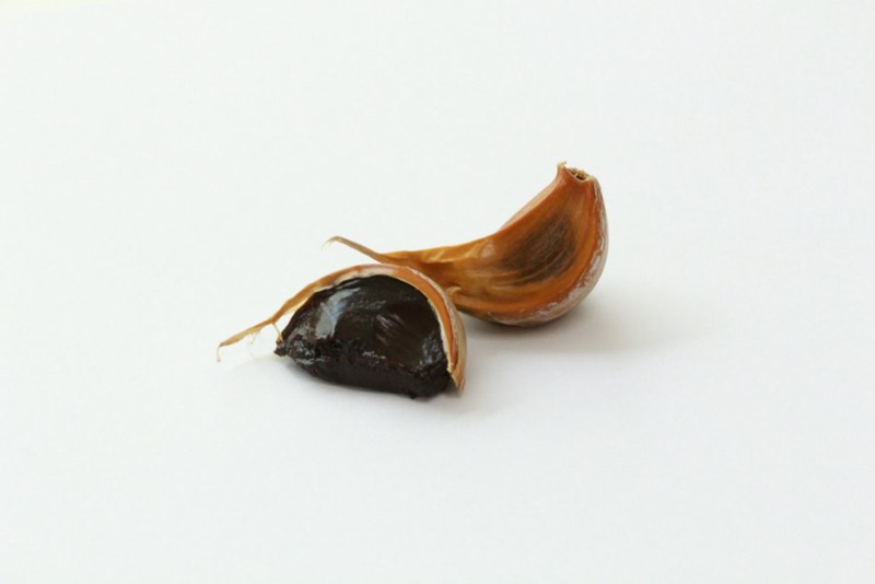 Two cloves of black garlic on a white background.
