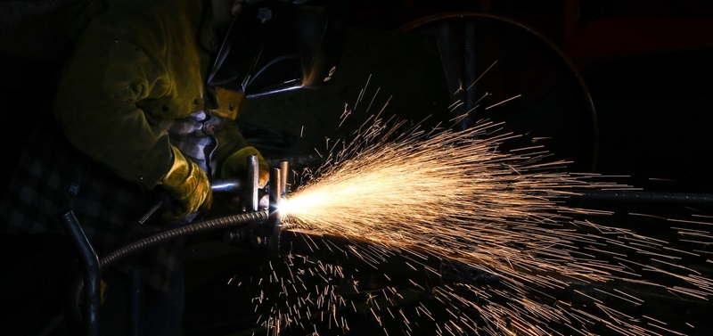 Image of man in suit and helmet arc welding.
