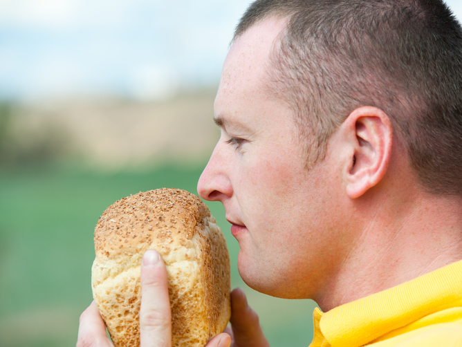 A men smelling a loaf of bread.