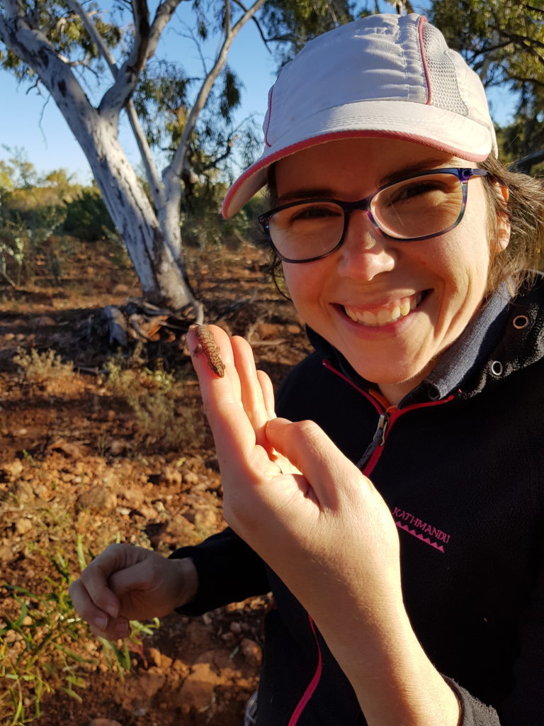 Mariana holding a small lizard smiling at the camera. 