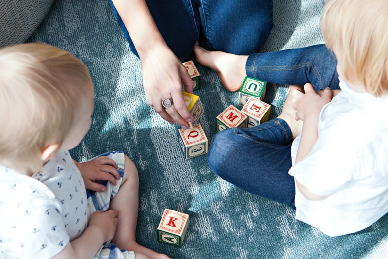 Lockdown tips for parents. Parent and two children playing with wooden alphabet blocks. 