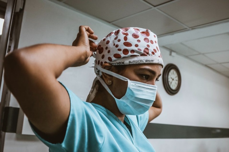medical person putting on surgical face mask