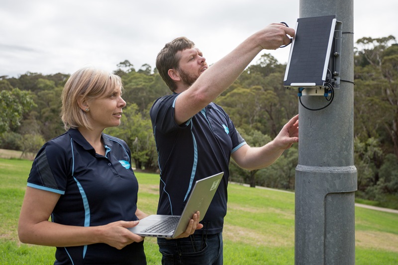 Researchers installing an air quality monitoring device onto a pole.