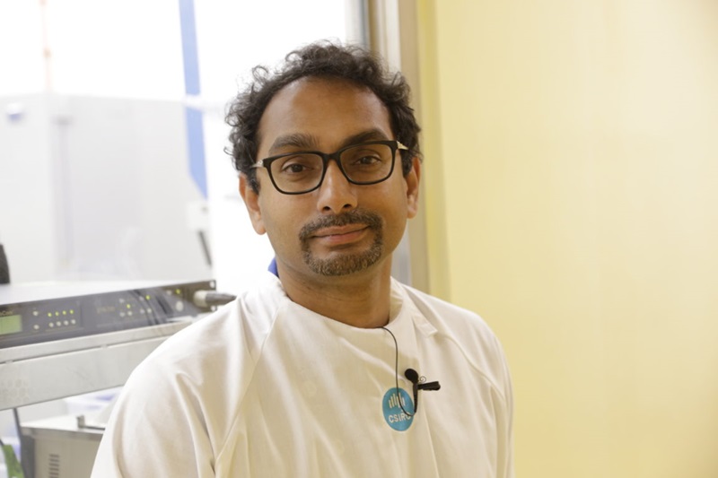Man in lab gear smiling at camera