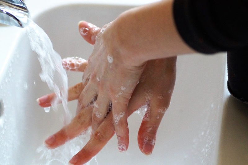 A person washing their hands with soap under a running tap. 