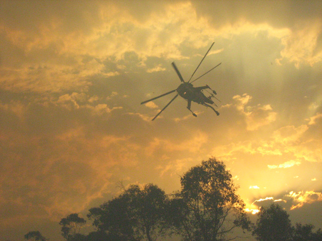 water bomber helicopter against bushfire smoke-filled sky
