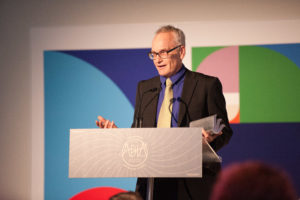 man in suit received award at podium