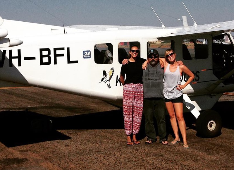 Three people in front of light plane