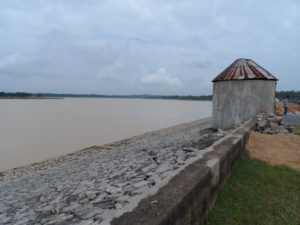 wide angle of muddy, wide river with storage structure in foreground