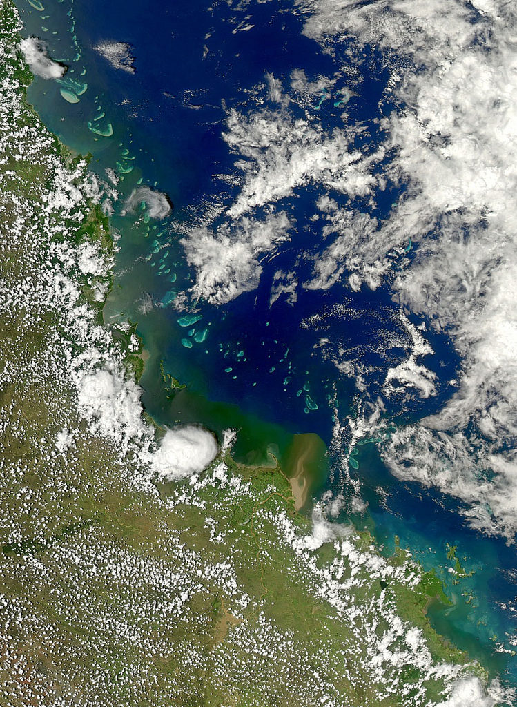 Queensland Coastline as seen from space shows the Great Barrier Reef and muddy water flowing from hte Burdekin River into the ocean.