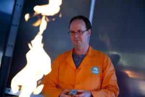 Man in orange coat looking at flame