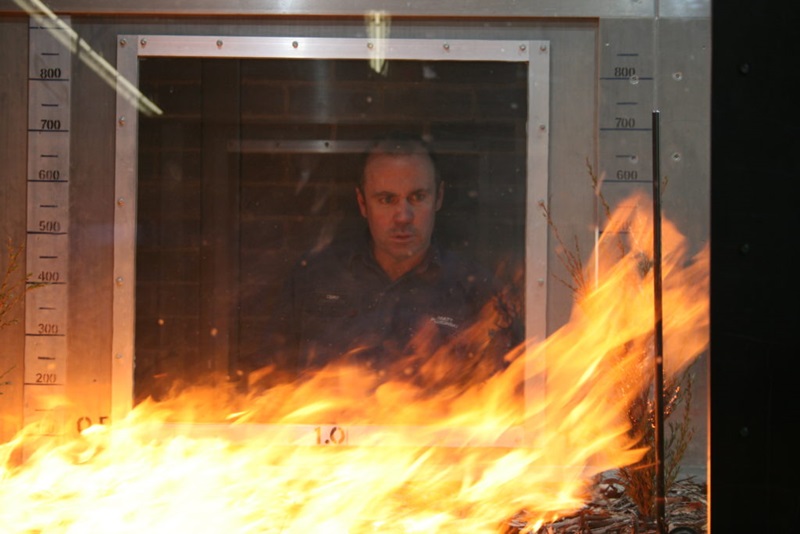 A man looking at a fire experiment - a big flame in a lab