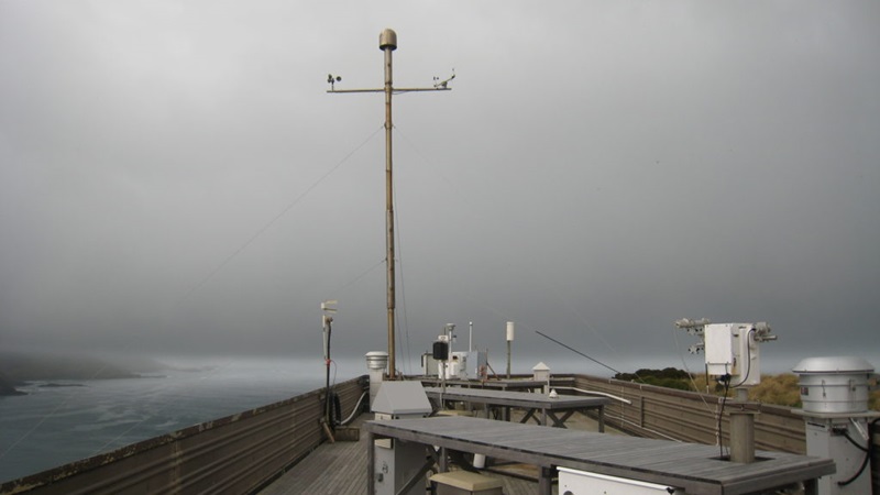 An array of scientific measuring equipment, with the ocean and coast pictured in the background