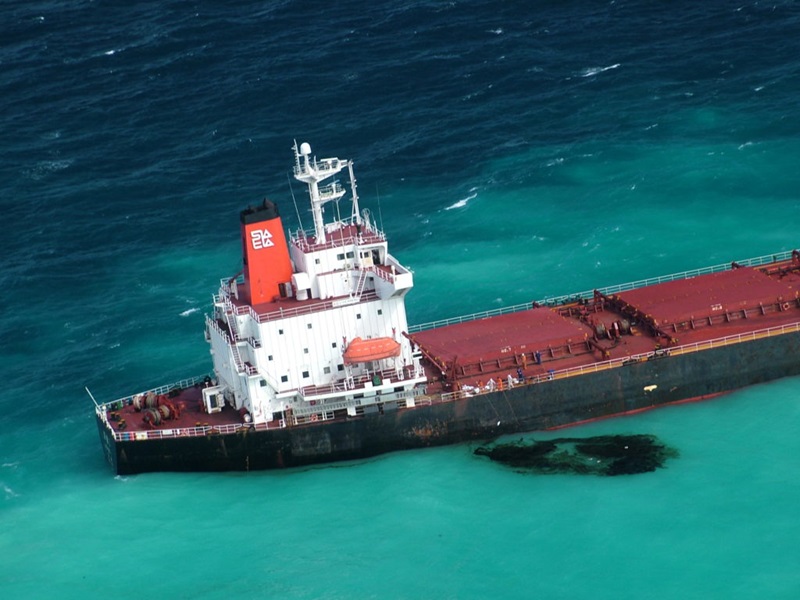 ship at sea with black oil spill in the water