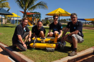 Four men posing with yellow mini-submarine