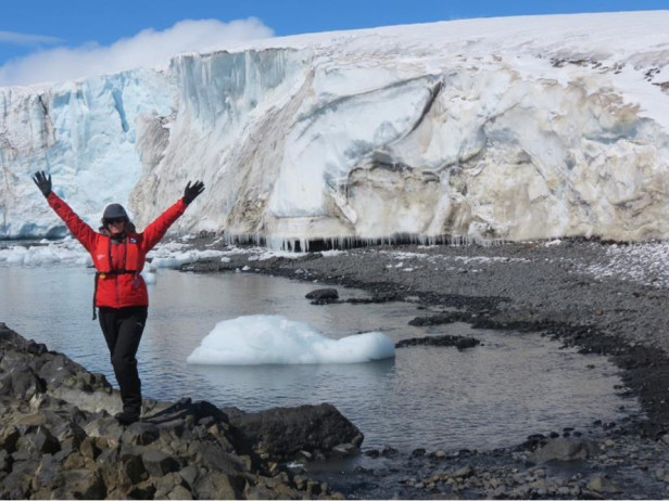 woman in red jacket in front of ice cliff