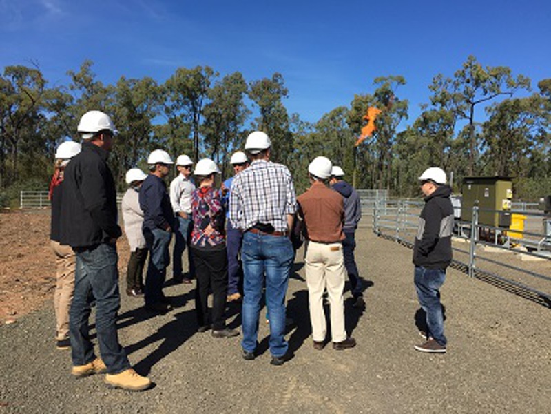 Group of people with hard hats on standing near a CSG well