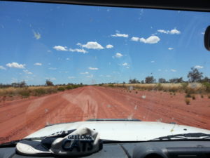 View through the windscreen from a car travelling on a remote dirt road 