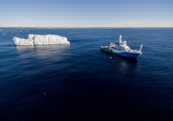 boat and ice berg in deep blue ocean