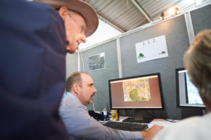 close up of three people in front of a computer showing a map