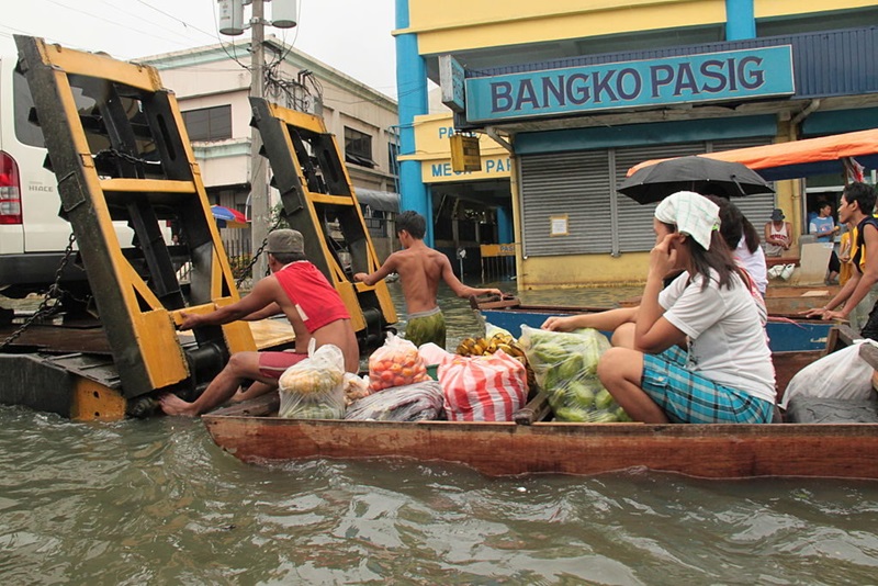 small boat with people and fruit and veg in flood waters