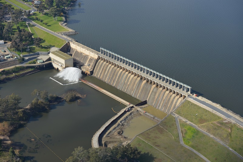 Aerial view of dam with lake on one side and spillway on the other
