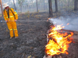 man in protective orange suit near burning log