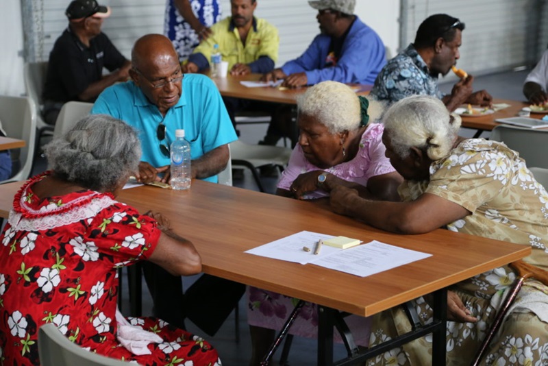 Four elderly people sit around a table