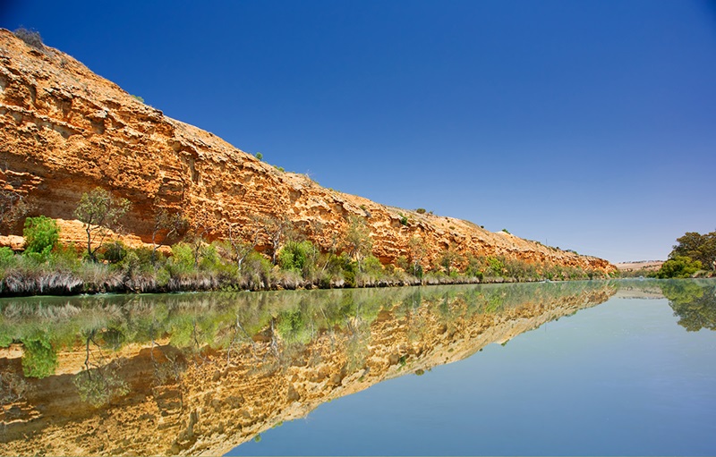 Sandstone cliffs reflecting in a wide river