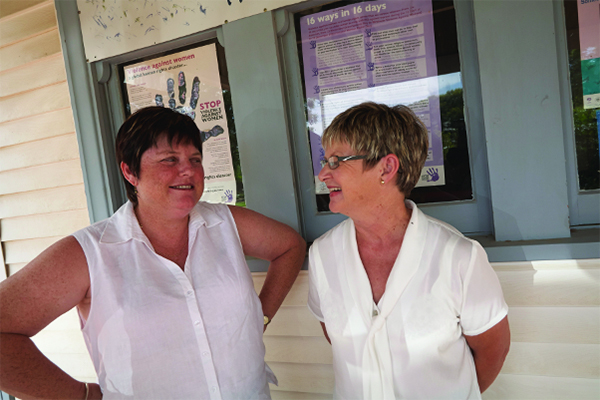 Two women in white tops standing on a porch